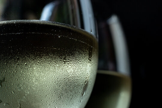 macro photo of two glasses of white wine. Two glasses with chilled wine in it and condensation and drops on them