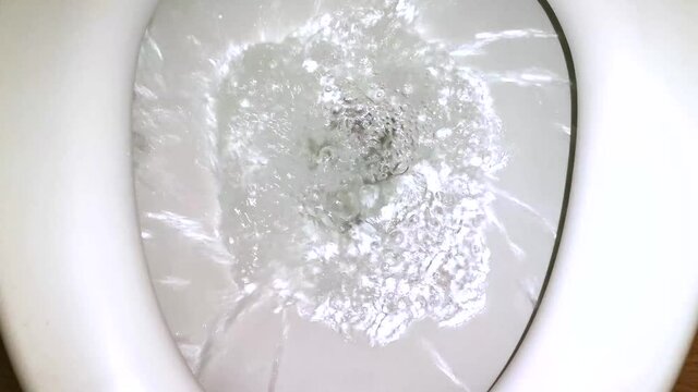 Press the toilet flush to clean. The water spins in a spiral. Slow motion.