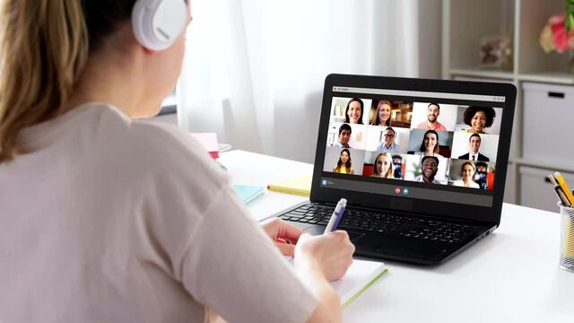 education, online school and distant learning concept - student woman in headphones with laptop computer having video conference at home