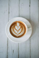 Latte art coffee on wooden table in coffee shop