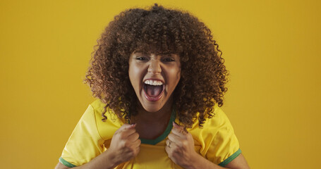 Brazil supporter. Brazilian curly hair woman fan celebrating on soccer, football match on yellow...