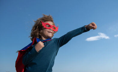 Fototapeta na wymiar Portrait of superhero kid against blue sky background. Copy space.