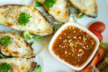 A traditional Thai style spicy seafood dipping sauce in white bowl which is served with cheese baked mussel menu. Food object photo.