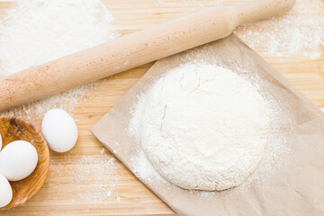 Raw yeast dough on a floured kitchen table, recipe idea. The concept of home baking or making dough. Rolling pin for dough