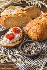 Mediterranean baguette with herbes and sel de mer, one slice with cream cheese and tomatoes, vertical