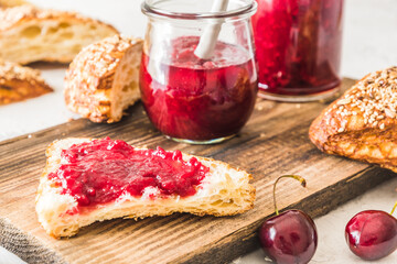 Homemade cherry jam on a lye roll on a wooden board