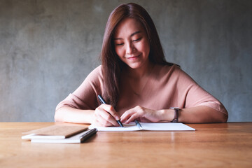 Portrait image of a beautiful young asian woman working and writing on notebook