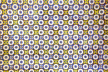 Traditional glazed blue, yellow and white ceramic tiles or azulejos which cover many buildings in...