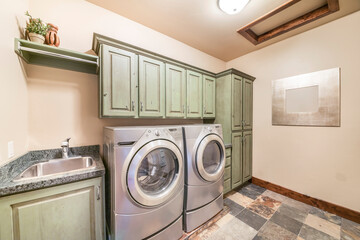 Laundry room interior with mint green cabinets and front load laundry appliances