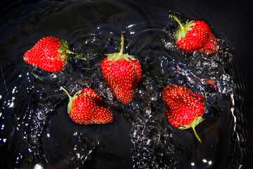 Red berry strawberry in water on a black background.