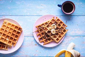 Breakfast waffle with banana on blue table