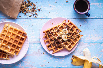 Breakfast waffle with banana on blue table