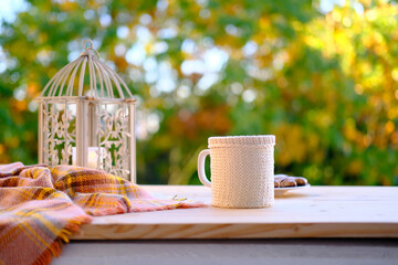 tea, coffee in a mug on the table in the garden, a candle is burning in a candlestick, the concept of outdoor tea drinking, good weather, a cozy autumn mood