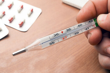 Man checks his body temperature using a mercury in glass thermometer