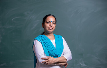 portrait of confident Indian teacher standing in front of the black board in class room