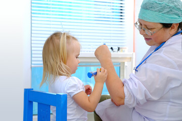 female doctor, pediatrician examines small child, 2-year-old girl with white hair, vaccinates, concept of preventive examination, treatment of children, covid-19 pandemic