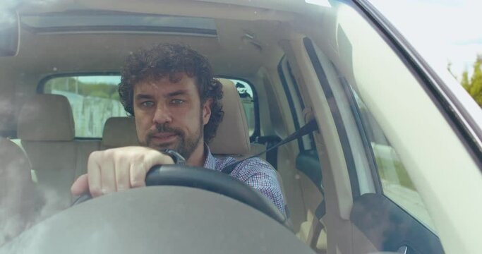 Tired young caucasian businessman is driving a car on a road. Going home after hard day. Car's interior. Front view.