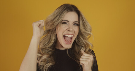 Fototapeta premium Young beautiful Caucasian blonde girl happily. Success and achievement concept. Cheerful pretty blonde woman on yellow background.