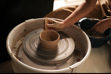 woman makes a plate on a potter's wheel. master class in pottery. creative workshop. hobbies and leisure