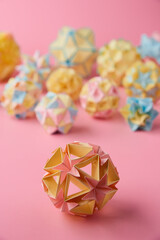 Set of multicolor handmade modular origami balls or Kusudama Isolated on pink background. Visual...