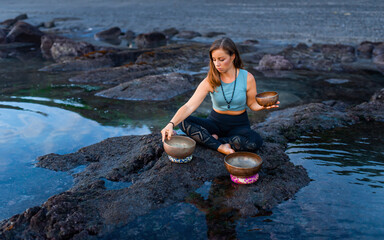 A girl plays on a Tebet musical bowl by the sea..