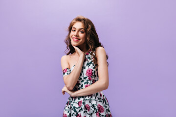 Smiling woman in pretty dress poses on isolated background. Beautiful lady with red lips and curly long hair looking into camera..