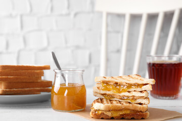 Tasty sandwiches with apricot jam and peanut butter for breakfast on white table