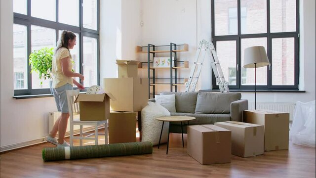 accommodation and real estate concept - young woman packing boxes at and moving out house