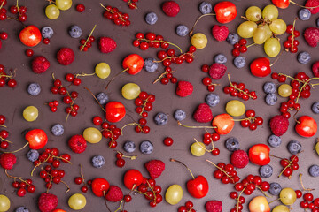 Assorted ripe berries, scattered on a black stone background