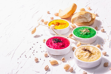 Various hummus dips, the flat lay of hummus in different colors with spinach, beetroot, turmeric and vegetables
