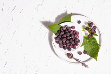 Black raspberry in a white bowl. Ripe organic fruits on the white putty background