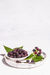 Black raspberry in a white bowl. Ripe organic fruits on the white putty background