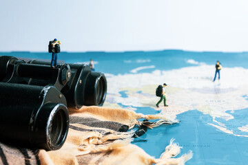 miniature traveler looking for travel place on binoculars. closeup. concept of world traveling.