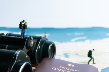 miniature traveler looking for travel place on binoculars. closeup. concept of world traveling.
