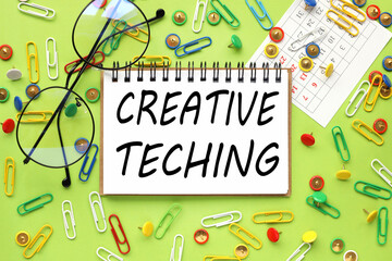 CREATIVE TECHINGб text on notepad on bright green background. near paper clips and buttons