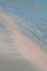 Pink paradise sandy beach with blue water as an abstract summer background.