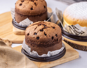Mini chocolate Taiwanese castella cake on white paper with wooden board.