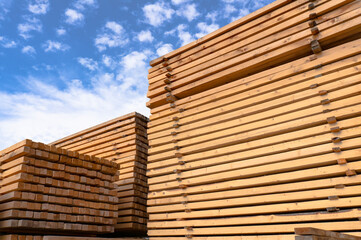 Wooden beams and boards against a bright blue sky. Warehouse and lumber shop
