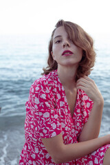 Fototapeta na wymiar Natural beauty of as young woman enjoying her holidays in a beach of the coast side in a pink vintage flowers dress.