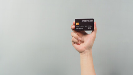 Hand is holding black credit card isolated on grey background.