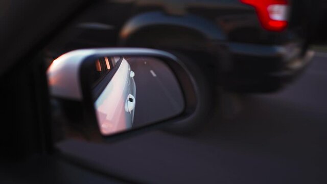 View in the side mirror of a car that is driving fast on the highway overtaking other cars.