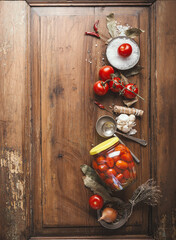 Tomatoes preserving.  Jar with fermented tomatoes on wooden table background with ingredients. Top view