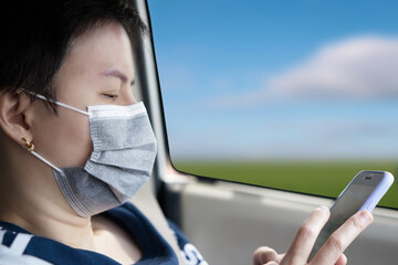 asian woman LGBT wear protect mask in car for new mormal life style use cellohone smartphone for...