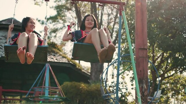 Asian girl in Thai cultural dress relaxing on a swing, Slow motion
