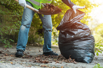 man volunteer clean up park or collect foliage with shovel in garbage bag