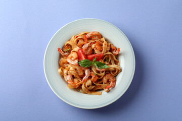 Plate of tasty shrimp pasta on violet background