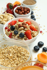 Bowl of oatmeal and ingredients on white background