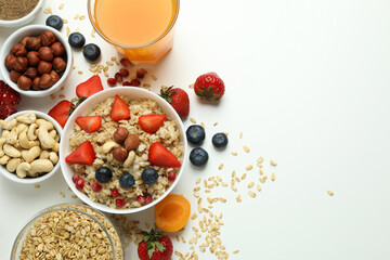 Bowl of oatmeal and ingredients on white background