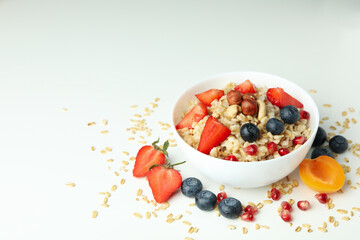 Bowl of oatmeal and ingredients on white background