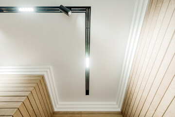 Bottom view of white ceiling with line lamp in the middle. Walls with wooden effect tiles - 445547557